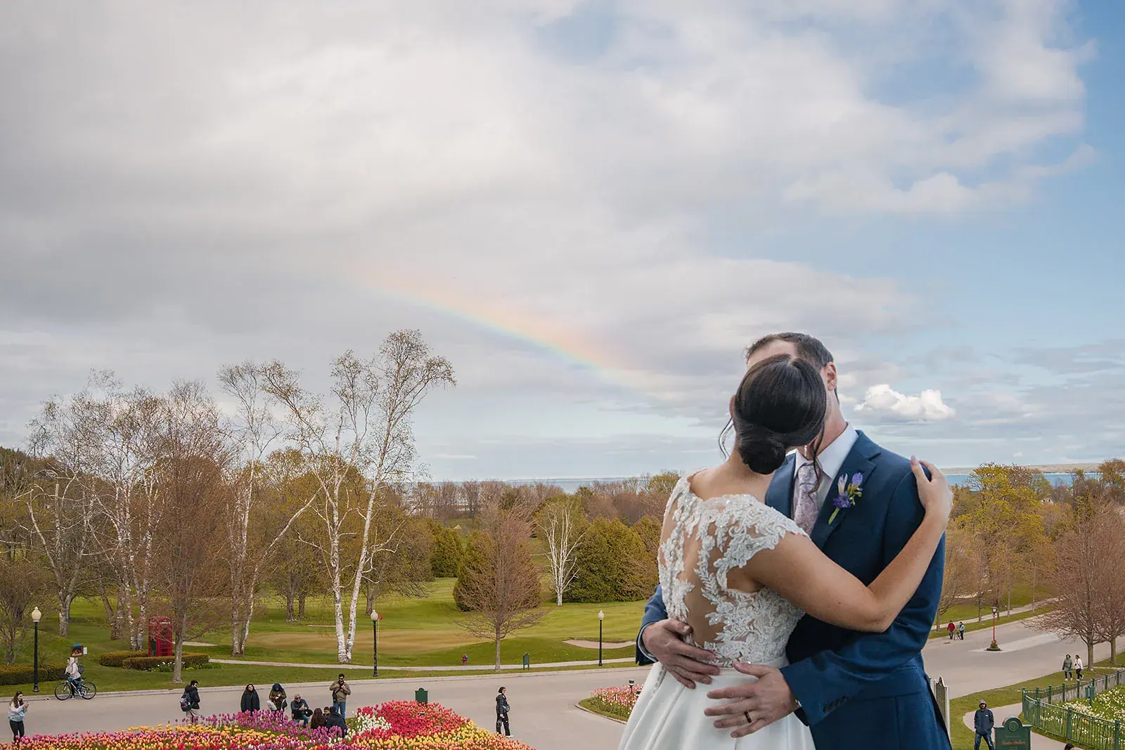 Bride and groom embracing on the Grand Hotel lawn on Mackinac Island, a rainbow overhead