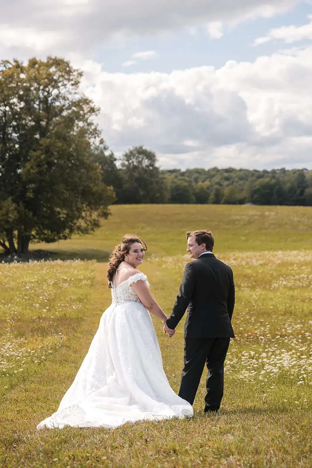 Bride and groom holding hands field — Amelia & Howard's wedding at Sunset Hill Wedding Barn, Central Lake