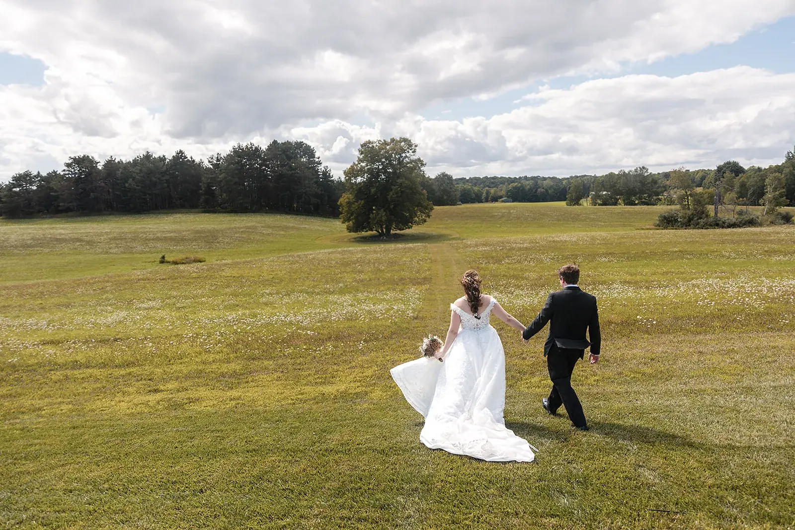 Bride and groom walking open field — Amelia & Howard's wedding at Sunset Hill Wedding Barn, Central Lake