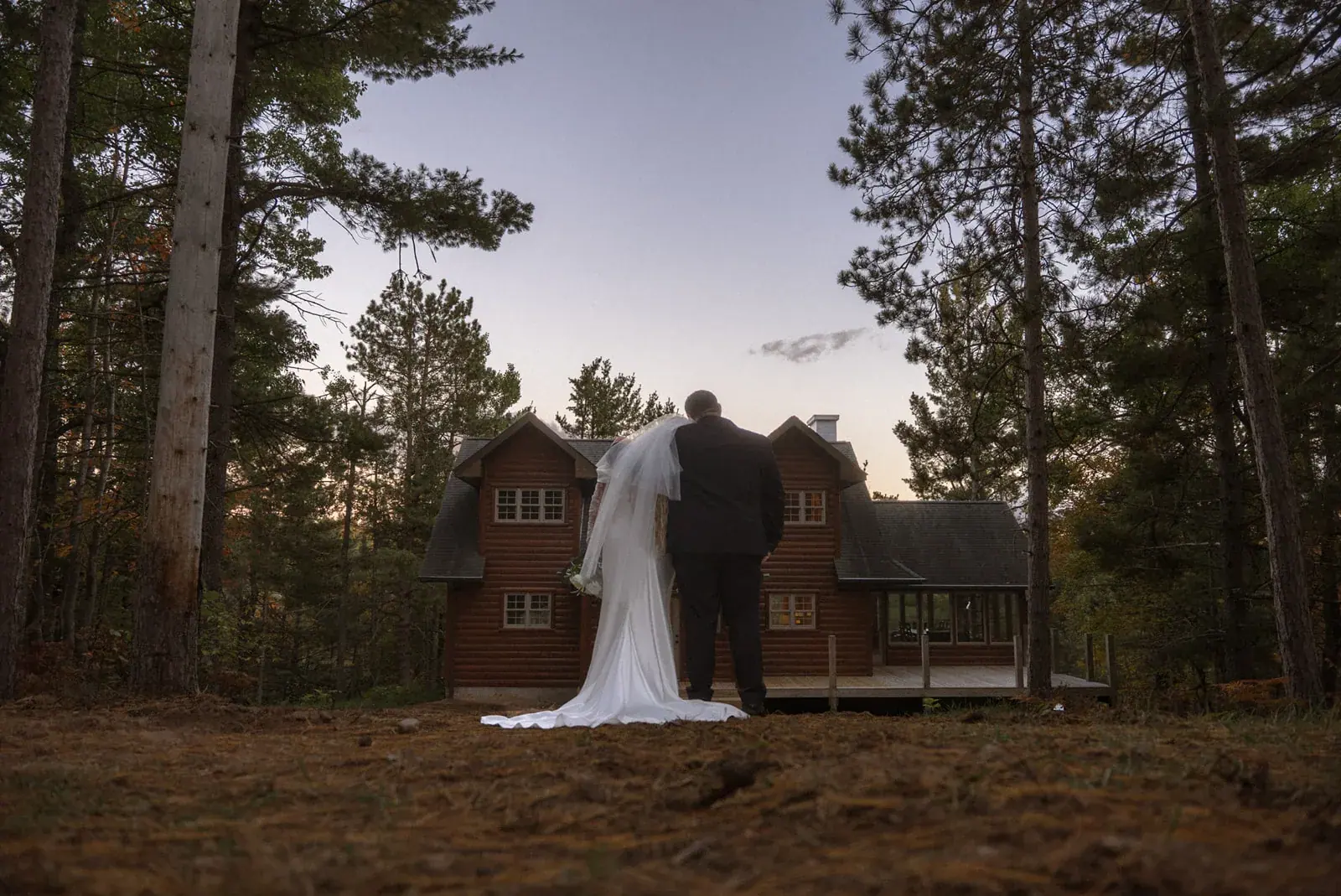 Bride and groom walking to log home dusk — Ann & Brad's wedding at their log home in Vanderbilt