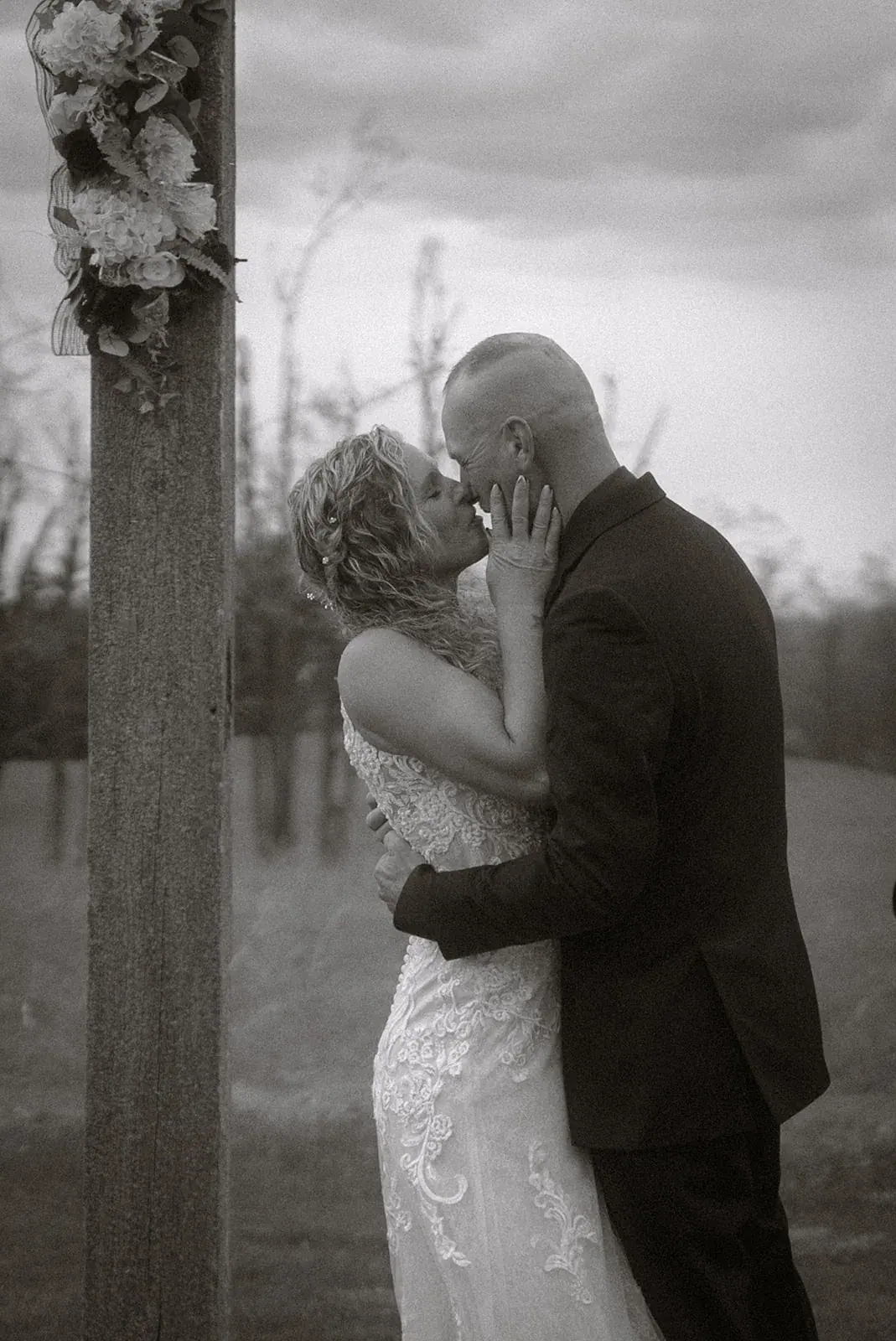 Bride and groom kiss arbor in black and white — Erin & Jim's wedding at Sonshine Barn, Gaylord