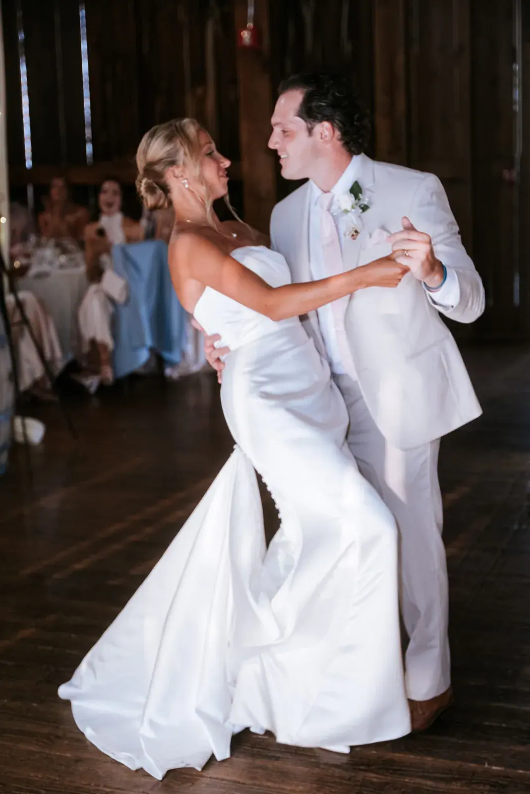 Bride and groom dancing on the barn floor while guests watch