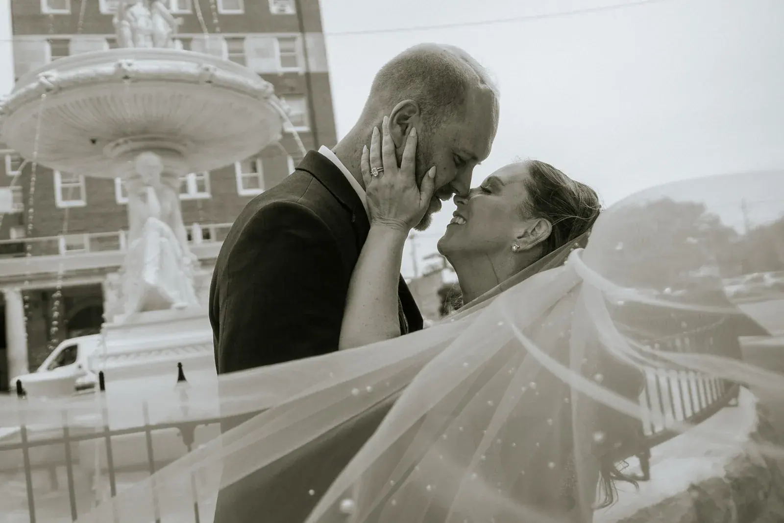 Bride and groom kiss fountain in black and white — Kelly & Ezra's wedding at Aria at The Whitcomb, St. Joseph