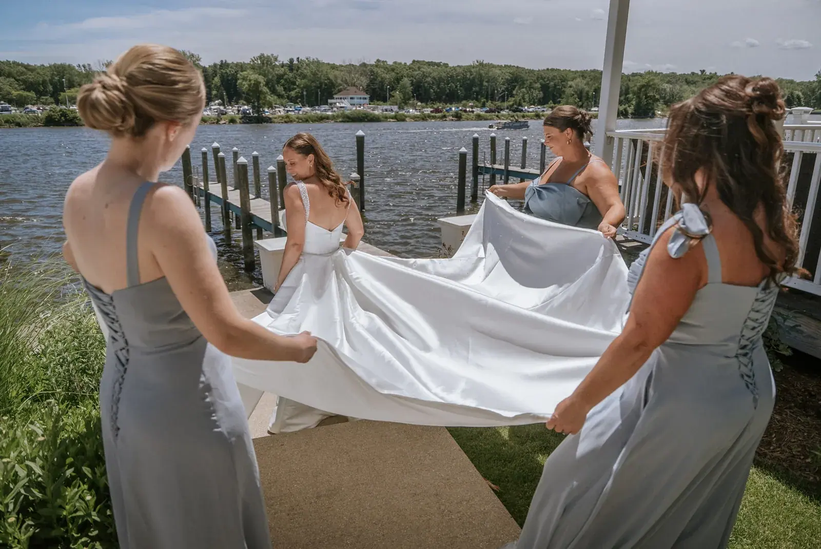 Bridesmaids carrying dress train waterfront — Kelly & Ezra's wedding at Aria at The Whitcomb, St. Joseph