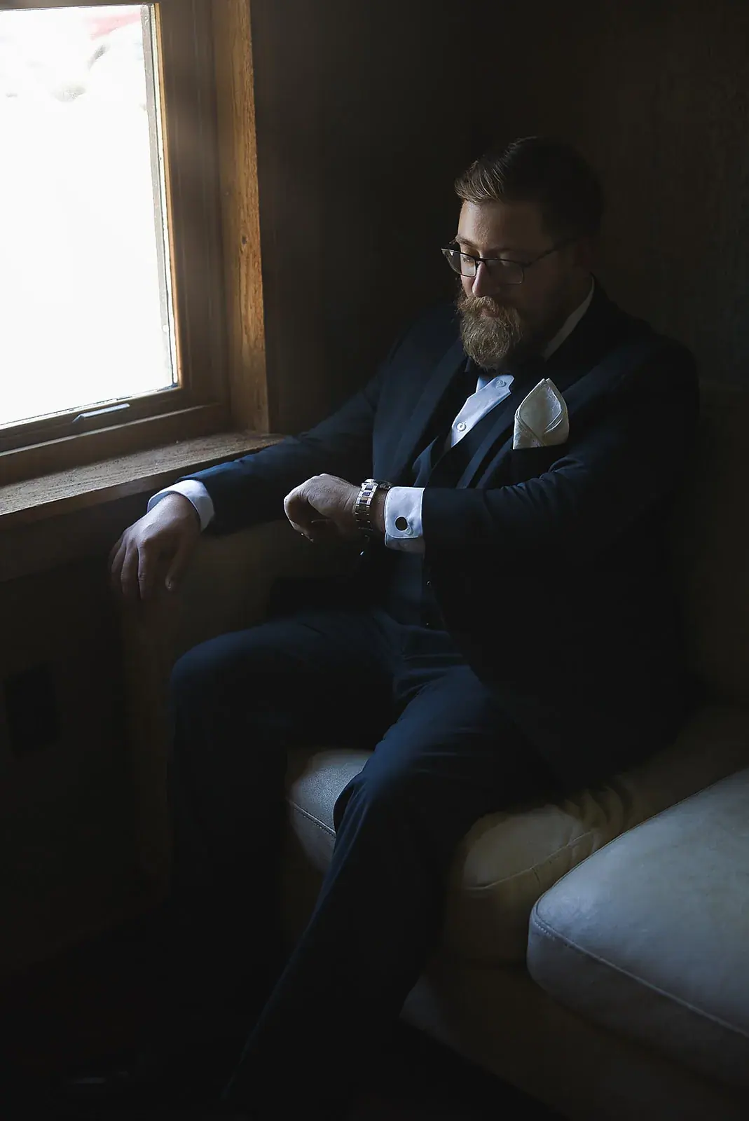 Groom seated window light — Megan & AJ's wedding at The Manor at Fire Tower Hill, Lewiston