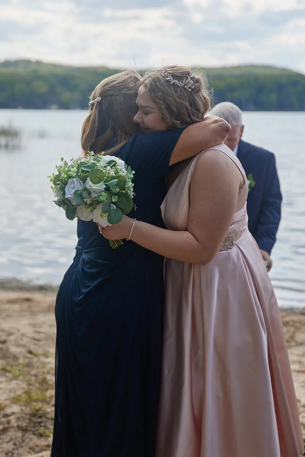 Bride hugging guest lakeside — Rachel & Alberto's wedding at Higher Ground at Lake Louise, Boyne Falls
